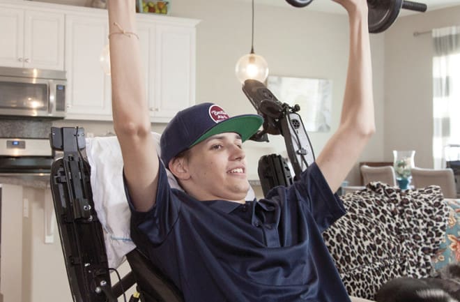 Kris Boesen, lifts a dumbbell over his head.